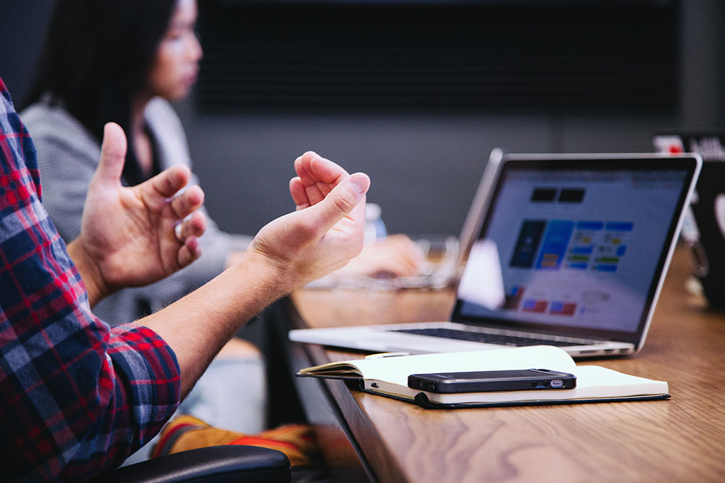 person hand gesturing at a laptop